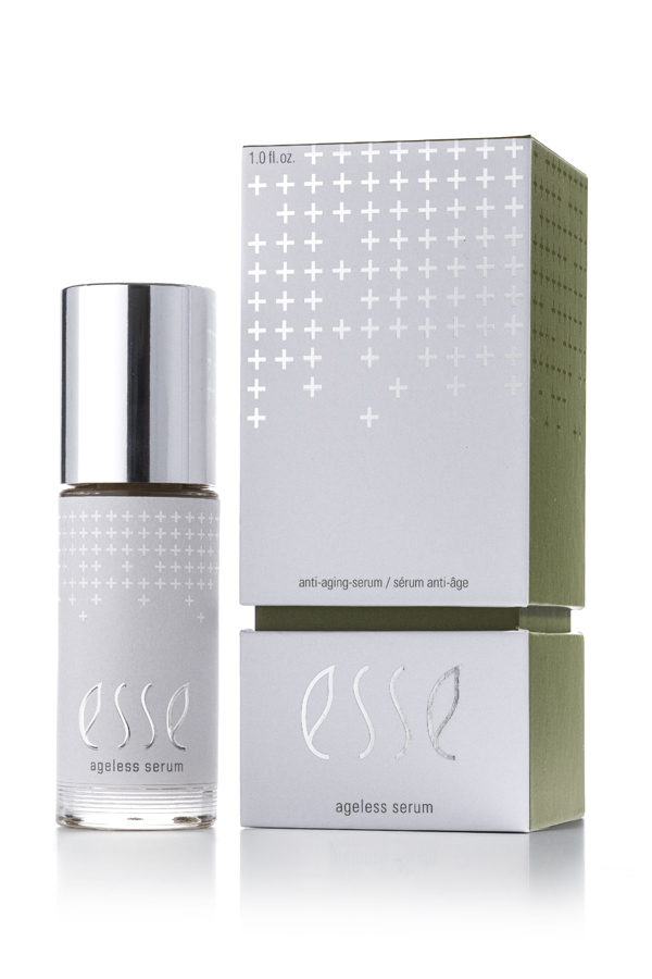 A bottle of Esse Ageless Serum with a silver cap stands beside its matching box, which displays silver cross patterns and minimalist text on a white and green background.