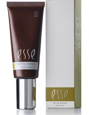 Next to its corresponding white and olive-green box sits a tube of Esse Refining Cleanser. The dark brown tube, featuring a silver cap and label detailing the product type and volume of 3.4 fl oz, matches the branding and details displayed on the box.