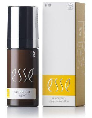 Photograph of the Esse Sunscreen set. The set consists of a bottle and its packaging box. The bottle is dark with a black and silver cap, labeled "esse sunscreen SPF 30." The beige box beside it features the same "esse sunscreen high protection SPF 30" label along with a chemical design pattern.